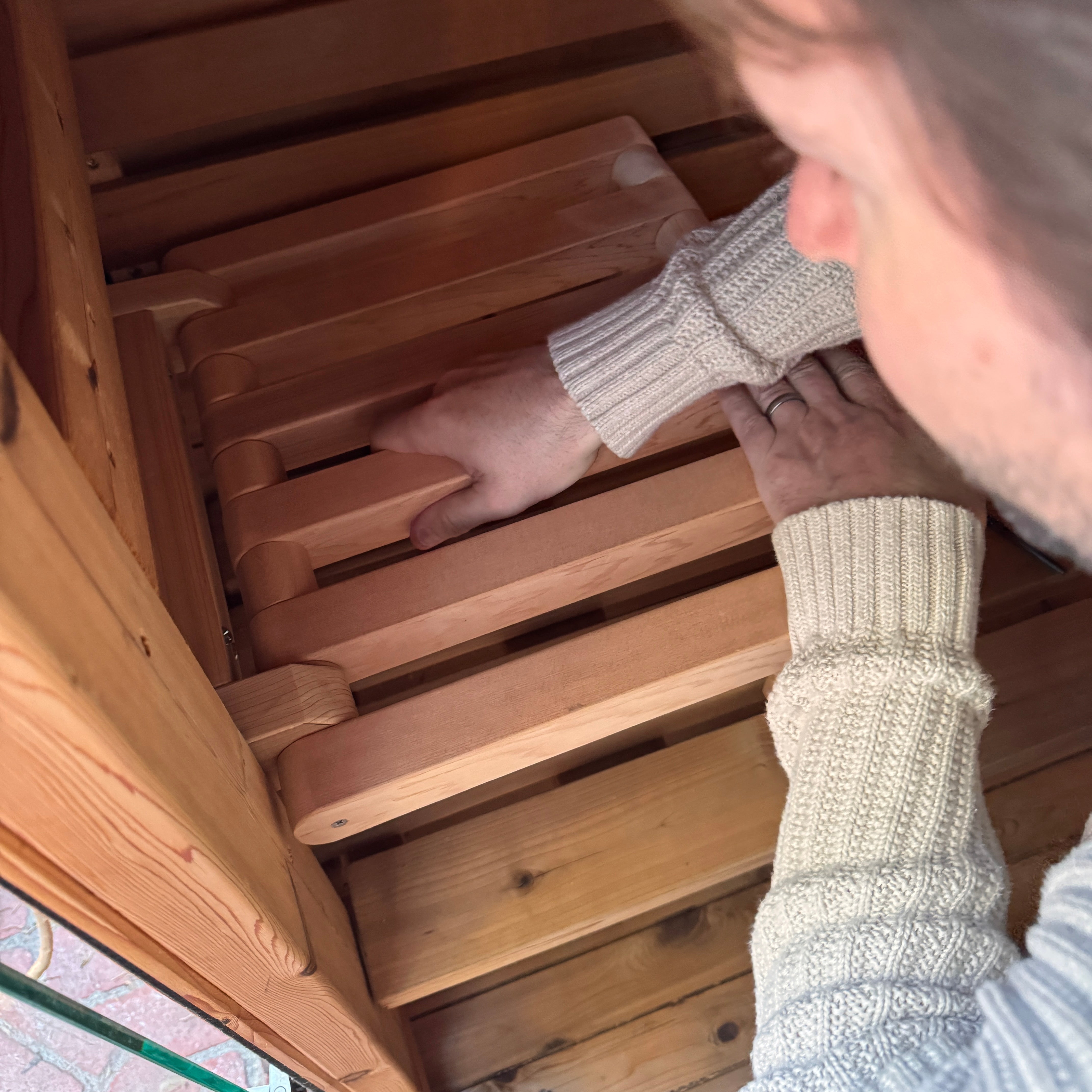 Person wearing a knit sweater interacting with Löy Sauna Seat